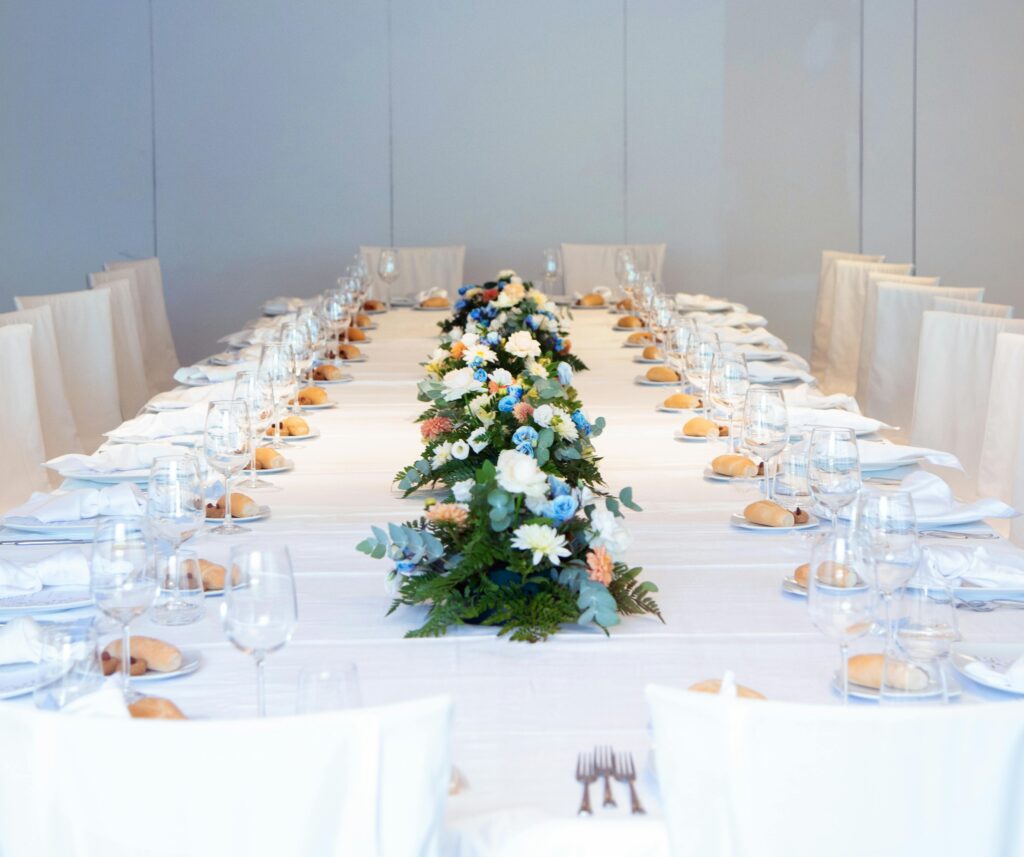 pexels-photo-28179592-28179592 Luxurious banquet table setting with a vibrant floral centerpiece, ready for an elegant indoor event.