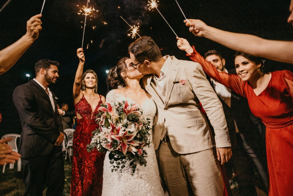 pexels-photo-3292697-3292697 A joyful couple kisses under sparklers, surrounded by guests in a wedding celebration.